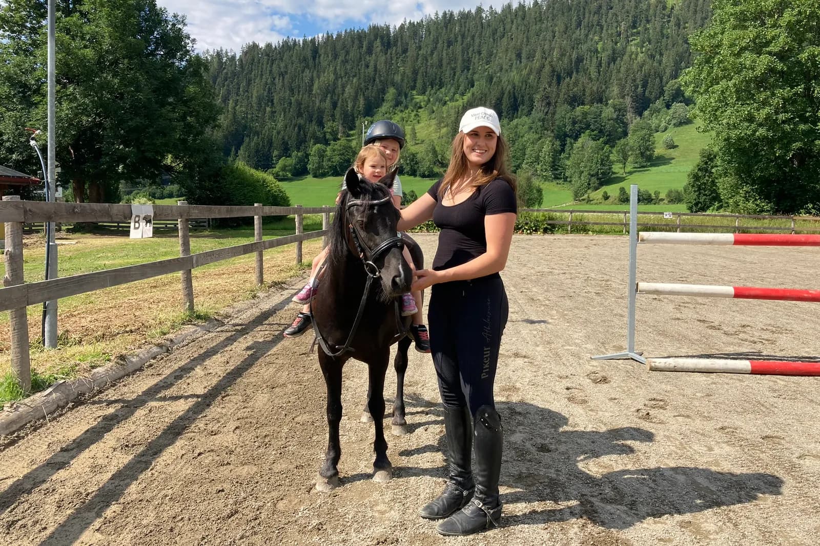Kind auf einem Pony mit Reitlehrerin am Reitplatz