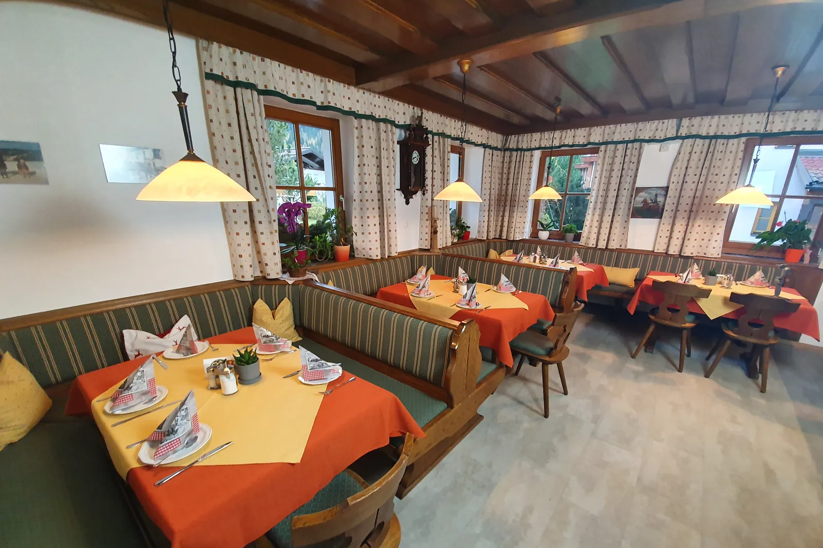 Breakfast room with set tables, corner benches and a wooden ceiling