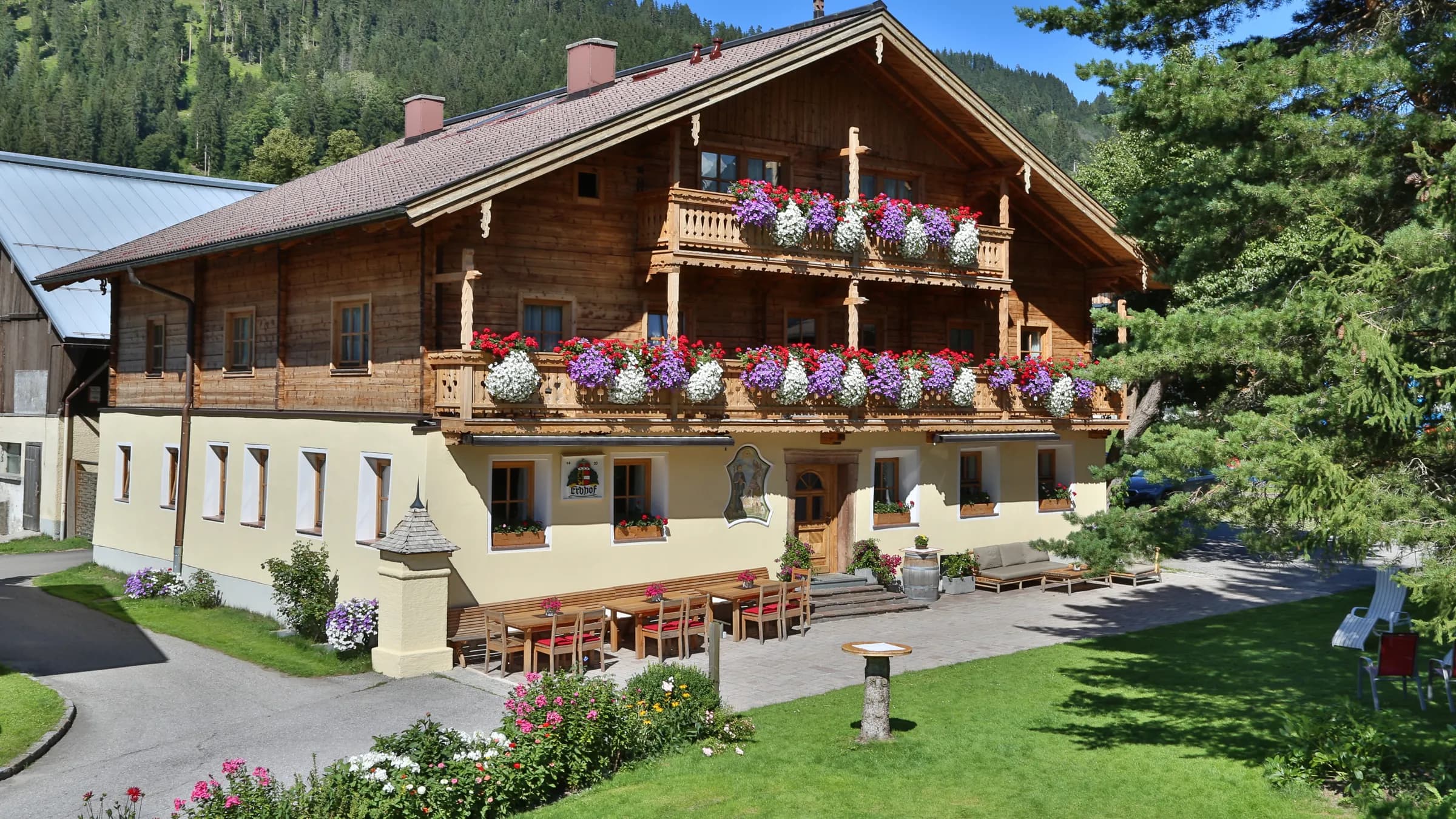 Das Stammhaus des Kasparbauer mit Hofkreuz, Holzbalkonen und Blumenschmuck im Sommer